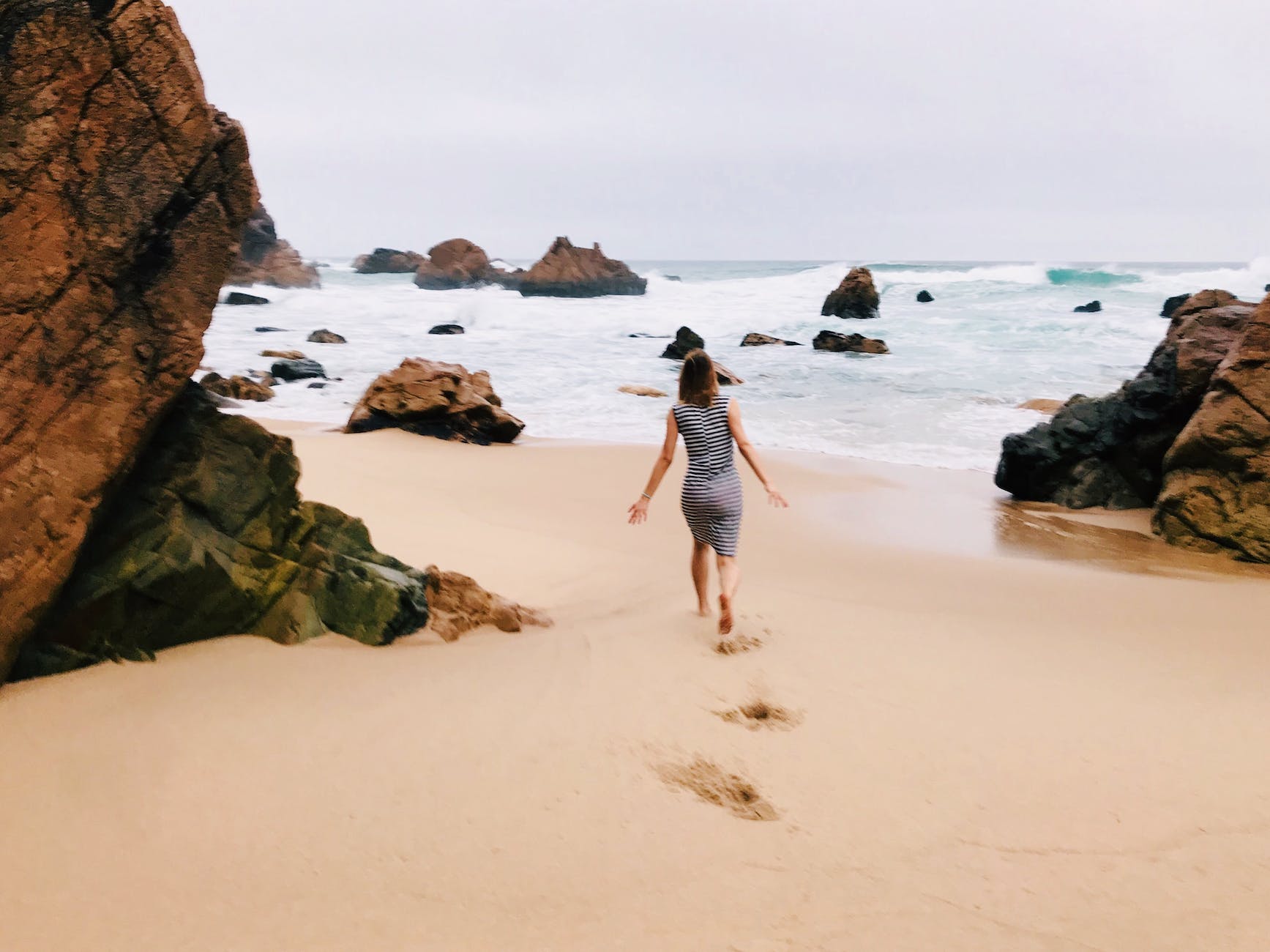 photo of woman walking on seashore