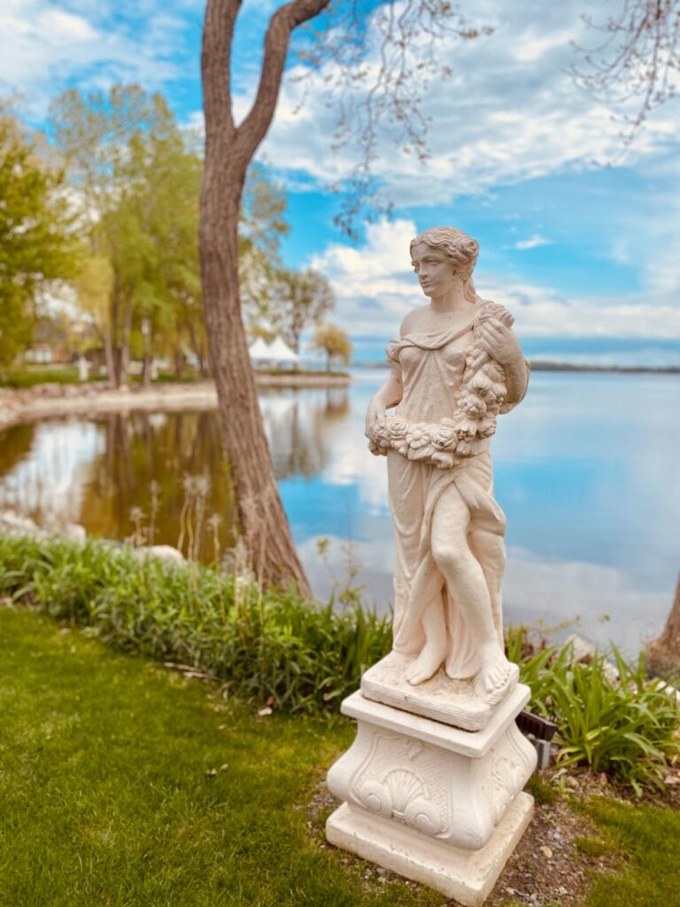 statue of a woman in dress near the body of water