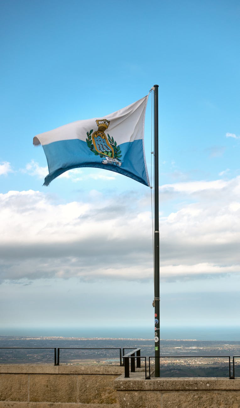 a flag flying high above a city with a blue sky