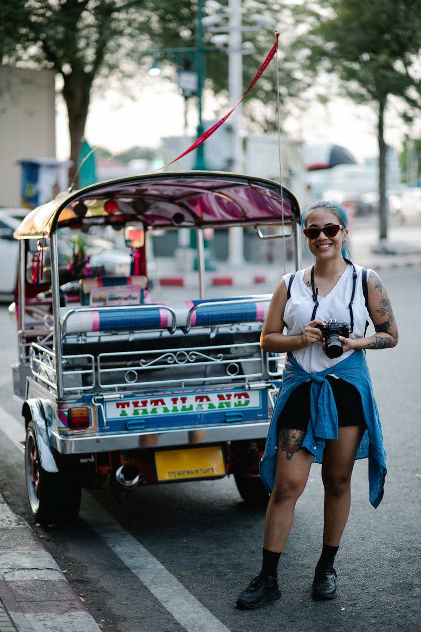 young woman tourist standing on a city street with a camera around her neck smiling
