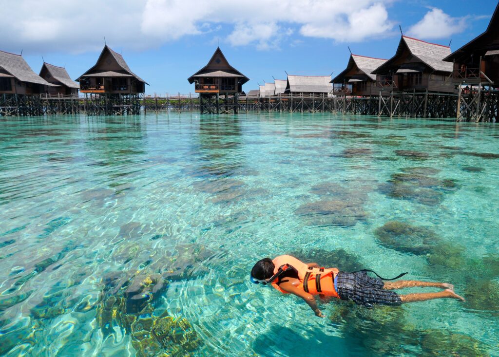 Ce que la Malaisie apprend aux familles qui refusent de choisir 25 A boy swims on clear crystal ocean fills with coral during vacation 1